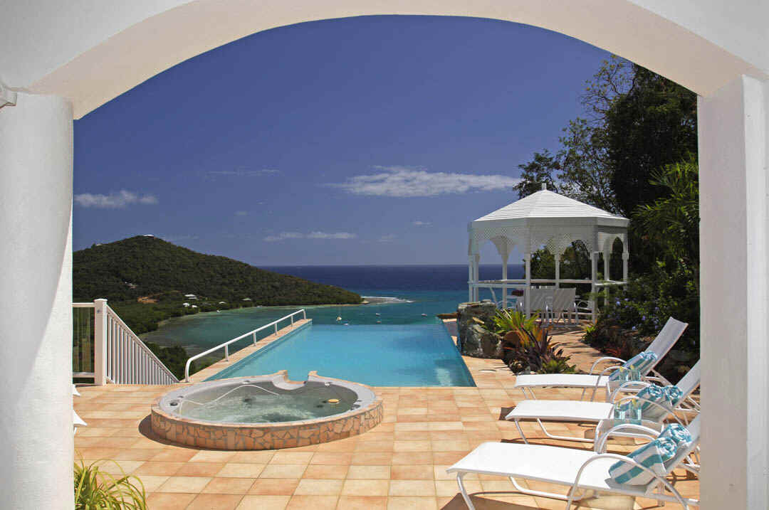 A serene view of the ocean from a patio, showcasing gentle waves and a clear blue sky.