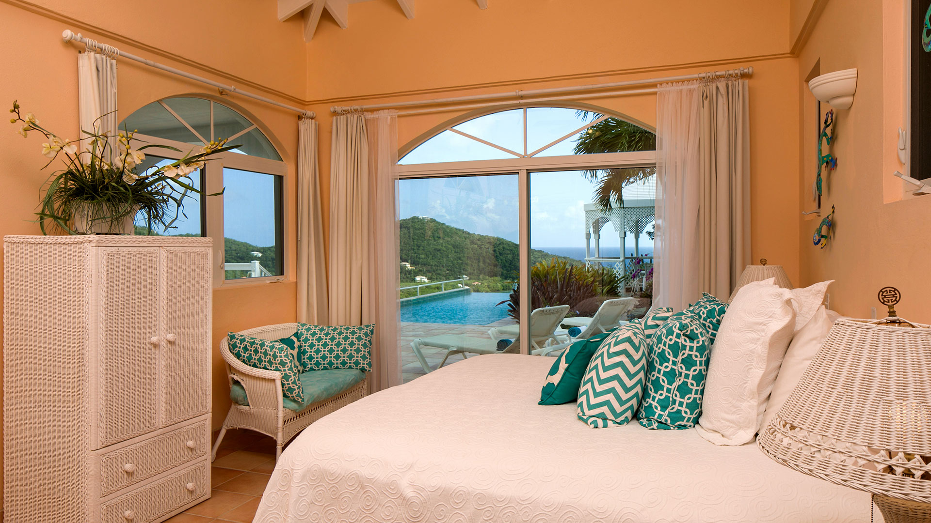 A serene bedroom featuring large windows that showcase a view of the pool and the ocean beyond.