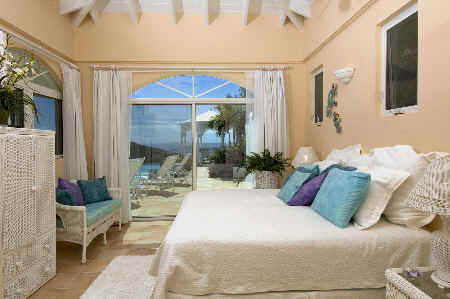 A serene bedroom featuring large windows that showcase a view of the pool and the ocean beyond.