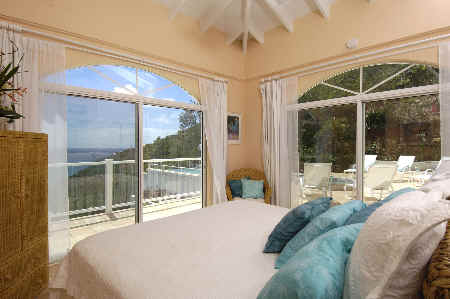 A spacious bedroom featuring a large bed and sliding glass doors that open to a scenic outdoor view.