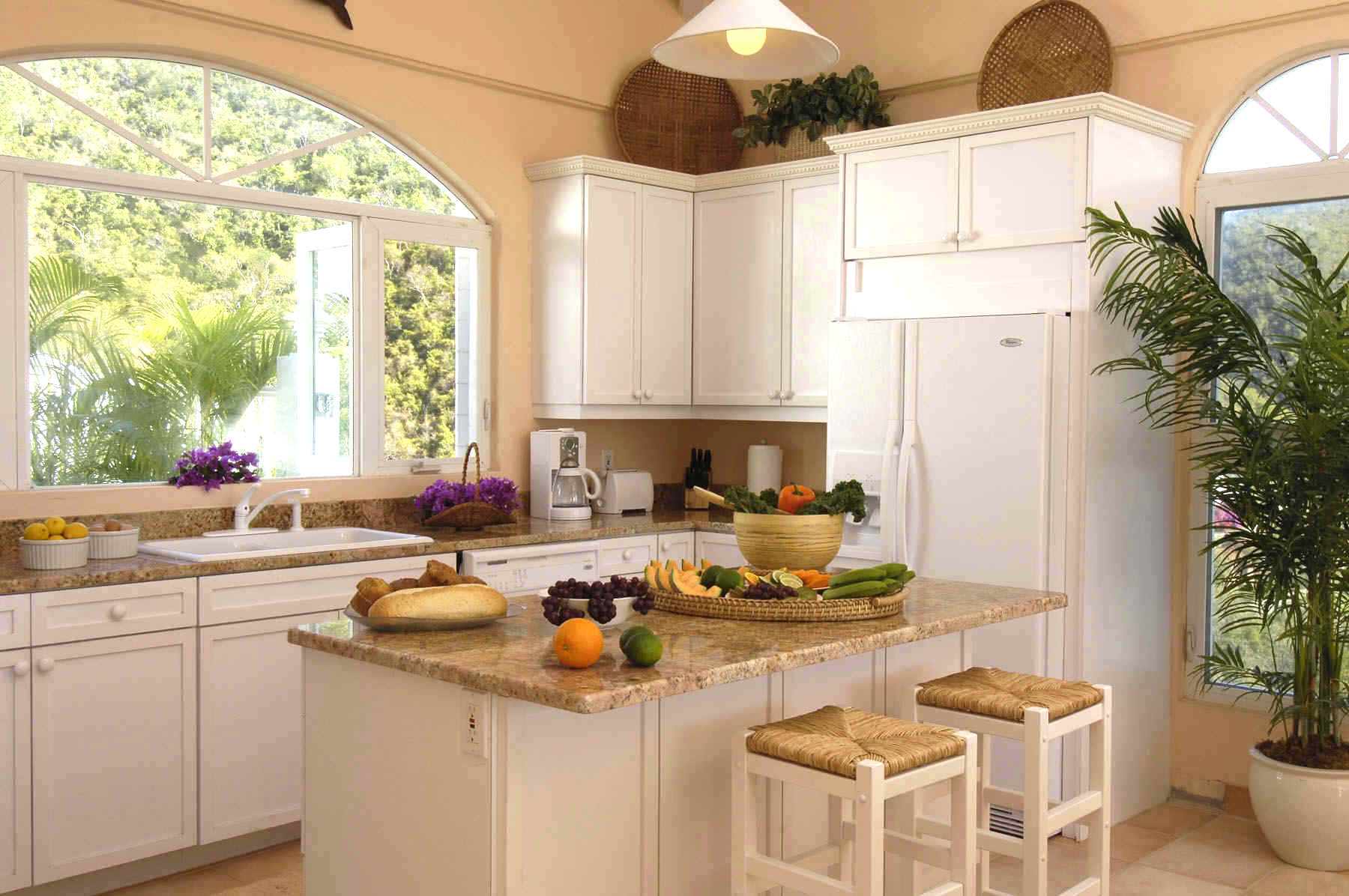 A bright kitchen featuring white cabinets and a large window that allows natural light to fill the space.