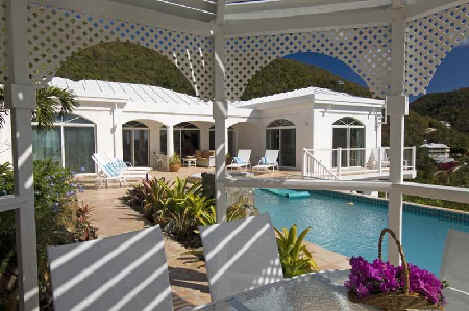 A gazebo featuring white furniture surrounded by a serene pool, creating a tranquil outdoor relaxation space.